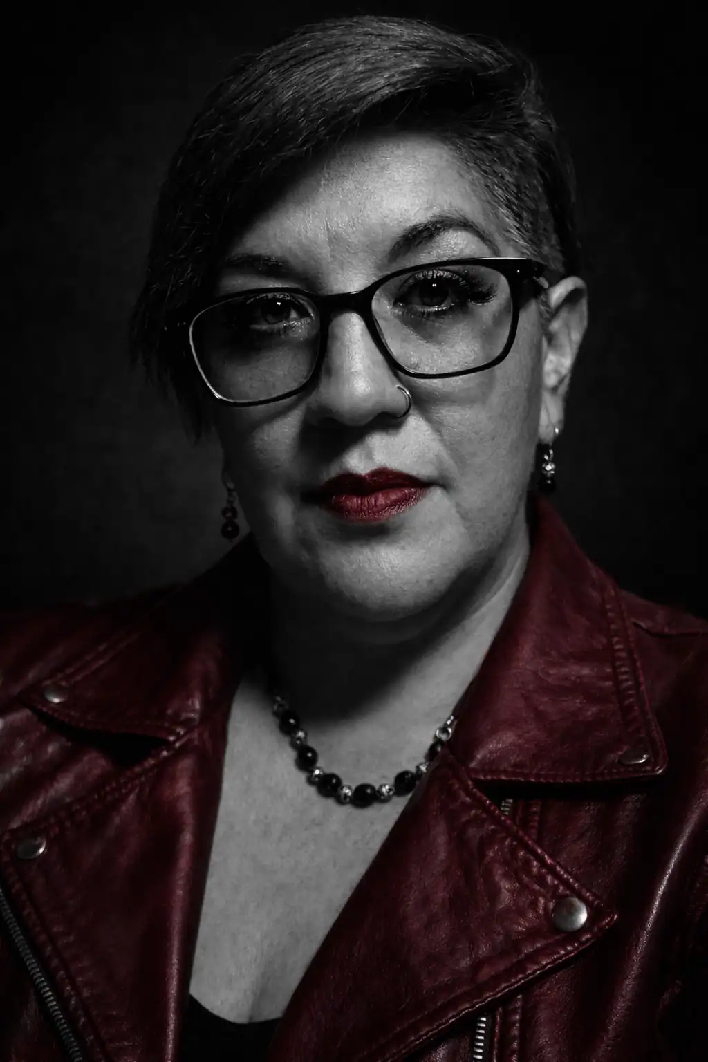 Portrait of Yeya wearing glasses and a red leather jacket in black and white.